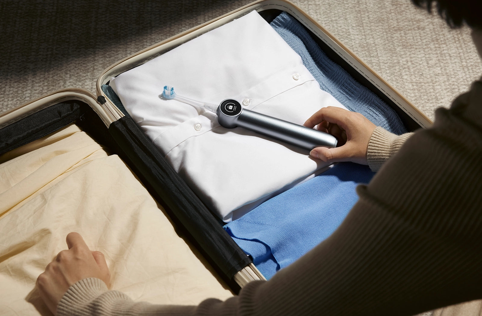A woman packs her AirJet electric toothbrush into her luggage with lock mode on.