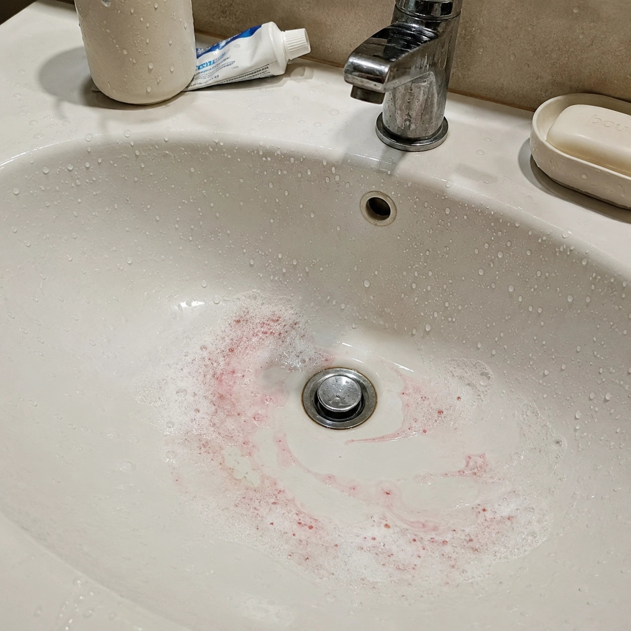 blood mixed with toothpaste foam in the sink